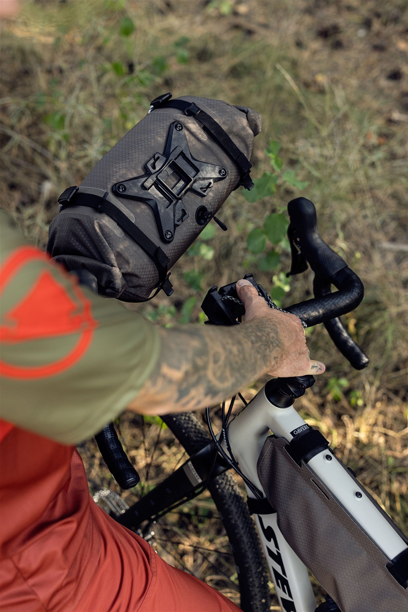 Cycliste roulant avec le sac de guidon ORTLIEB Handlebar-Pack Flex couleur dark-sand sur chemin forestier
